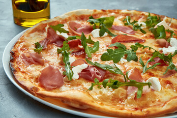 Italian pizza with jamon, arugula and cream cheese on a gray background. Selective focus, food flat lay