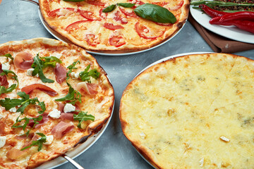 Photo for the pizzeria menu. Three different pizzas margarita, four cheese and with jamon on a gray background.. Top view. Food flat lay
