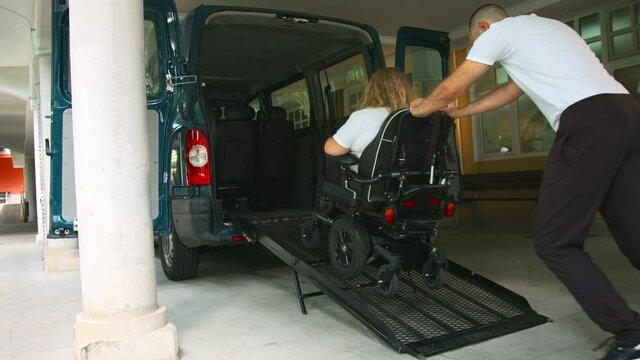 Wheelchair user leaving vehicle adapted for disabled transport with ramp and lift.