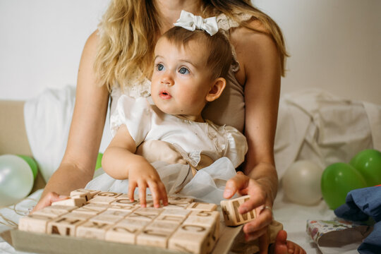 Little girl playing with wooden ABC blocks. Plastic-free wooden zero waste kids toys for safe and sustainable gifting. Eco friendly, plastic free toys for toddler.