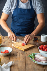 chef with apron cutting tomato on a rustic wooden table