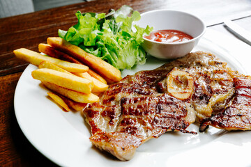 Pork Chop Steak Grilled steaks, French fries and vegetables