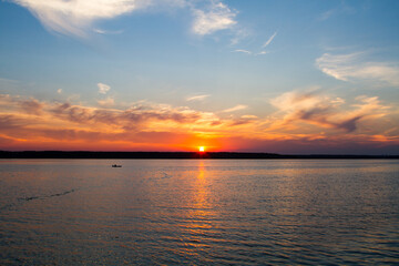 Obraz premium Sunset on the lake. A fisherman is fishing from a boat