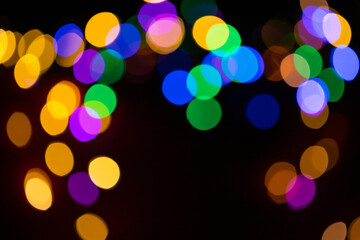 Christmas multicolored lights in defocus on a dark background