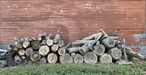 stack of firewood against old faded red barn wall 