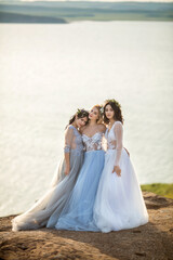 three beautiful females in wedding dresses in nature