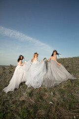Fototapeta na wymiar three beautiful females in wedding dresses in nature