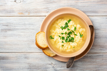 Italian stracciatella egg drop soup with parmesan cheese and parsley in bowl on rustic wooden...