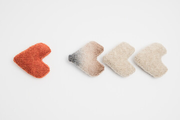 4 knitted hearts folded into an arrow on a white background