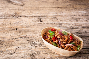 Mexican barquita taco with beef, chilli, tomato, onion and spices on wooden table	