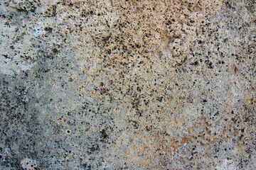 background from a block of wall carved from stone aged with splashes and streaks of gray and brown colors