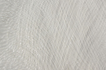 background of white travertine surface covered with flowing clear water with waves