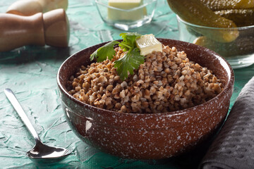 Boiled buckwheat with butter. Ready-made buckwheat in a deep dish on the table. Buckwheat with pickles.