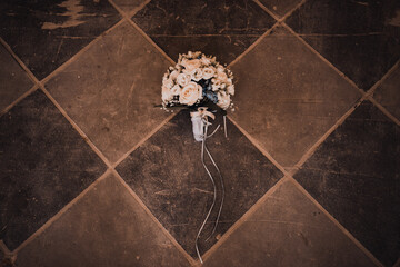 Wedding floral bright beautiful bouquet with small flowers in a wrapper lies on a brown wooden floor background.