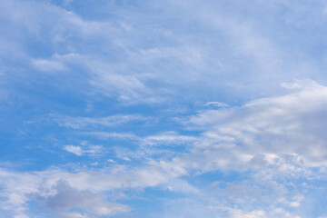 Blue summer sky with a lot of white cirrus clouds. Natural background made of cloudscape with sunlight.