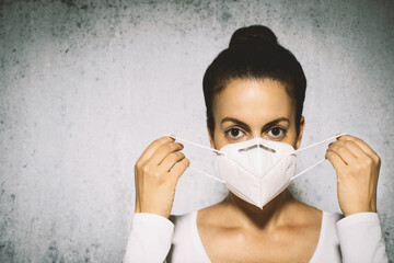 Woman putting on a medical mask to avoid contagious viruses.
