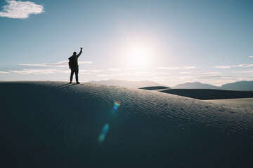 Unrecognizable man standing with arm raised in sandy desert