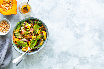 Fresh vegetable and pumpkin salad in a plate on a white stone background. Top view