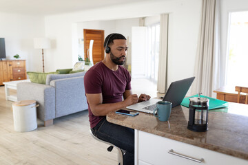 Man wearing headphones using laptop at home