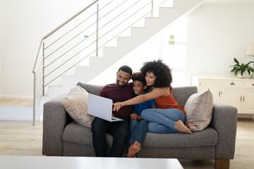 Fototapeta premium Family using laptop while sitting on couch at home
