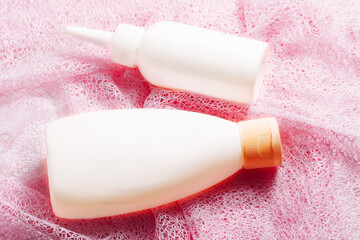 Cream moisturizer, lotion, facial cleanser or shampoo on pink  background. Mockup white plastic container for cosmetic product with copy space