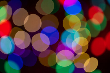 Christmas multicolored lights in defocus on a dark background