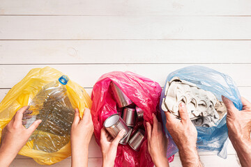 Recycling and ecology - people sorting household waste into bags