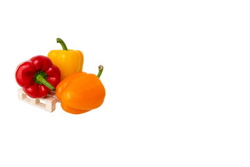 Close up of three fresh paprika standing on wooden mini pallet isolated on white background with large copy space.Sweet colorful bell peppers.Concept of selling products in vegetable store department