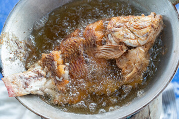 Fried fish on pan with boil oil. Thai local food.