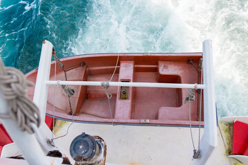 Rescue boat fixed on the ferry ship against the background of sea foam. Selective focus, top view