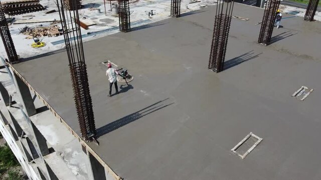 Worker in top of building construction with Power Trowel Tool Finishing Concrete Floor, Smooth Concrete Surface.