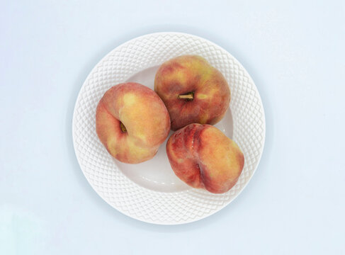 VIEW OF THREE FRUITS CALLED PARAGUAYAS FROM ABOVE ON A WHITE PLATE