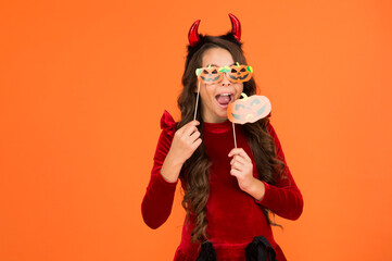 Happy kid on Halloween wear funny carnival costume and glasses indoor biting squash, happy halloween