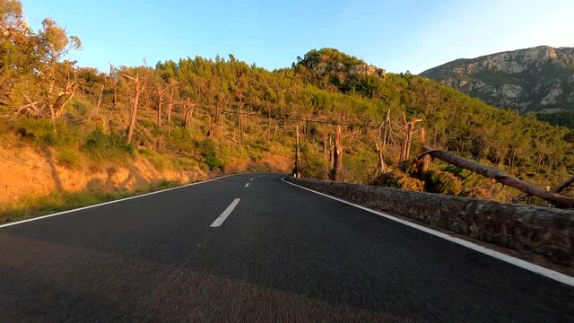 POV car driving along a winding road through mountains at sunset in Majorca island (Spain)