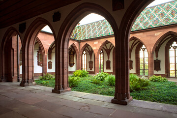 Fototapeta na wymiar Green plants in inner courtyard of Basel Cathedral. Cloister with archway and inner garden. Switzerland.