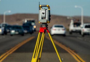 Land survey equipment set up on road with road becoming a hill in the background with traffic
