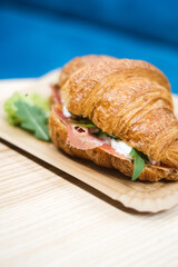 Croissant with ham and cheese arugula and lettuceon, in a paper plate top view