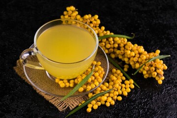 A cup with medicinal sea buckthorn tea on a black background.
Close-up.