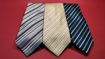 Trois elegante cravates rayées de couleur jaune grise et bleue sur un fond rouge