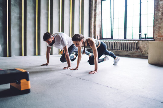 Trainer And Sportswoman Doing Plank Crunches Exercise In Gym