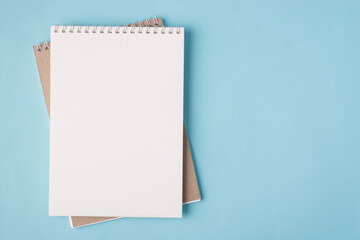 Top above overhead view flat lay photo of a blank notebook placed to the left side isolated on pastel blue color background with copyspace