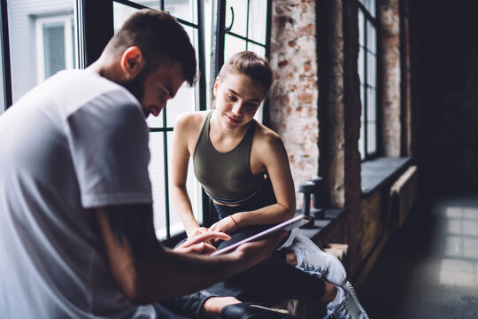Focused male showing tablet to sportswoman - Powered by Adobe