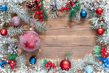 Christmas decoration with spruce branches with a red and blue ball on wooden background. Winter holiday light decoration. Top view.