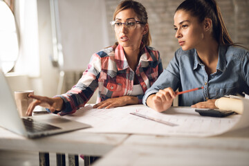 Fototapeta premium Young creative businesswomen working on blueprints in the office
