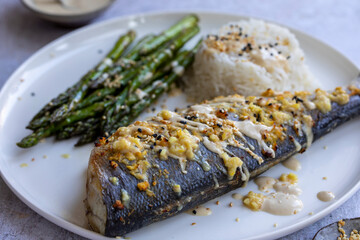 Baked sea bass with lemon grass, ginger, tahini sauce and sesame seeds