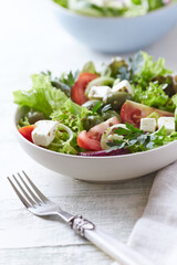Salad with Green Olives, Tomatoes and Feta Cheese. Bright wooden background.