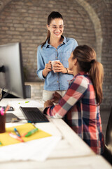 Two young businesswomen cooperating while working on desktop computer in the office