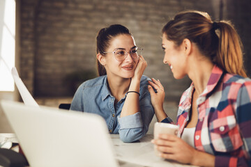 Young smiling businesswoman talking to her colleague about new reports in the office