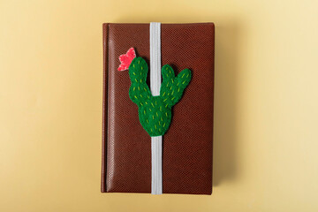 A shaped cactus bookmark  for  book are on a yellow background. Small felt toy green cactus.