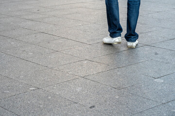 Sidewalk. Walking man legs wearing white shoes and jeans, motion blur. Selective focus, copy space for text.